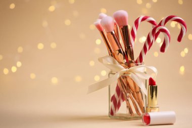 Ruj, fırça ve bej arka planda şeker kamışları, Noel ışıkları, mesaj için yer. Bokeh etkisi