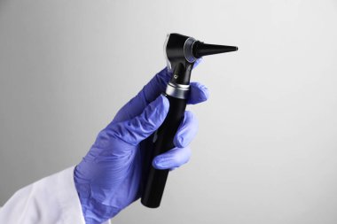 Açık gri arkaplan üzerinde otoskop olan doktor, yakın plan.
