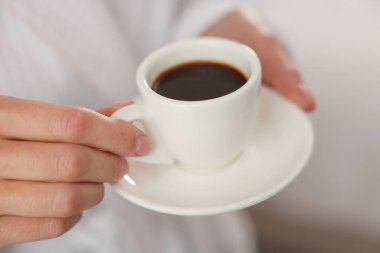 Bornozlu kadın, sabah kahvesi içeride, yakın plan.