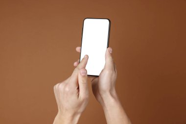 Kahverengi arka planda boş ekranlı akıllı telefon tutan adam, yakın plan. Tasarım için model