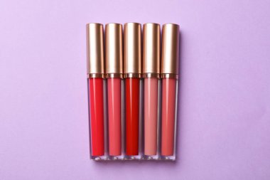 Leylak arkaplanda farklı dudak parlatıcıları, düz yatış