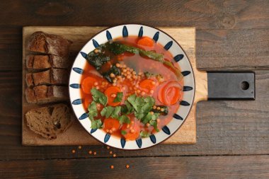 Lezzetli mercimek çorbası kasede ve dilimlenmiş ekmek ahşap masada, düz yatıyordu.