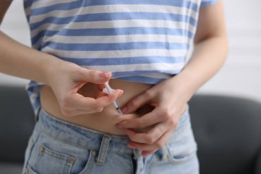 Tüp bebek için. Kadın karnına iğne yapıyor, kapalı alanda, yakın çekim.