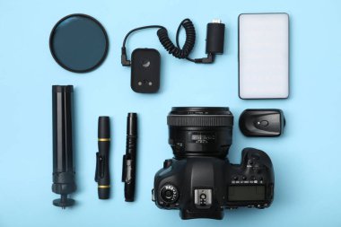 Açık mavi zemin üzerinde profesyonel fotoğrafçı ekipmanı, düz yatıyordu