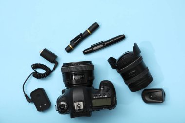 Açık mavi zemin üzerinde profesyonel fotoğrafçı ekipmanı, düz yatıyordu