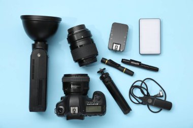 Açık mavi zemin üzerinde profesyonel fotoğrafçı ekipmanı, düz yatıyordu