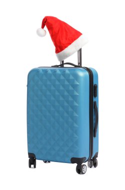 Noel tatili. Beyaz arka planda Noel Baba şapkası olan mavi bavul