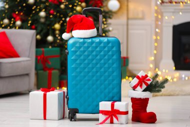 Christmas vacation. Suitcase with Santa hat and gift boxes indoors