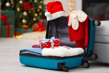 Noel tatili. İçinde Noel Baba şapkası, kıyafet ve hediye kutuları olan bavul.