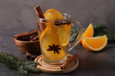 Lezzetli, portakal, baharat ve köknar dallı beyaz şarap koyu dokulu masa üzerinde gri arka planda, yakın plan