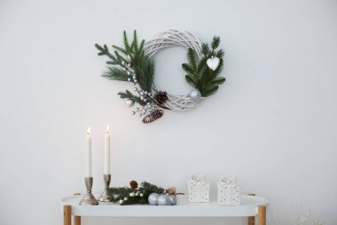 Noel süsü ve yanan mumlar beyaz duvarın yanındaki konsol masasında. İç tasarım