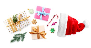 Gift boxes and sweets flying out of Santa hat on white background