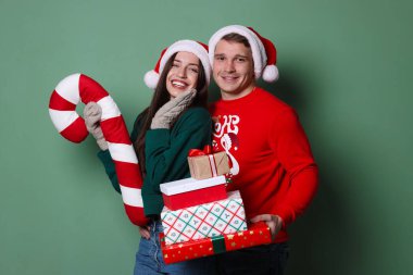 Noel Baba şapkalı mutlu çift ve yeşil arka planda dekoratif şeker kamışı.