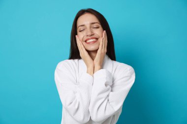 Açık mavi arka planda bornoz giyen kadın.