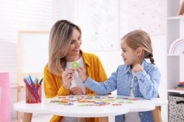 Anne, kızına beyaz masada alfabe öğretiyor.