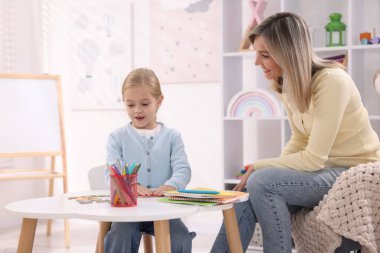 Anne, kızına beyaz masada alfabe öğretiyor.