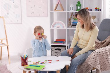 Anne, kızına beyaz masada alfabe öğretiyor.