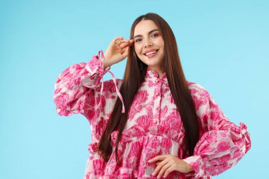 Açık mavi arka planda güzel giyimli bir kadın.