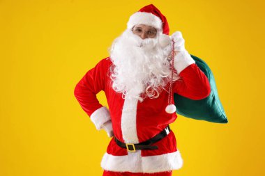 Sarı arka planda çantası olan Noel Baba. Mutlu Noeller ve mutlu yıllar.