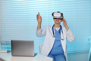 Modern teknoloji. Ofiste masasında sanal ekran kullanan kulaklıklı bir doktor.