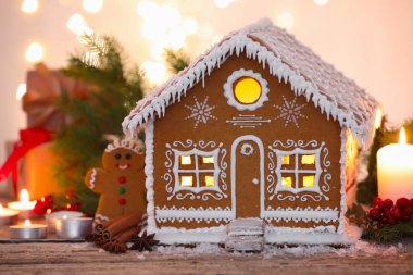 Güzel zencefilli kurabiye evi ve ahşap masanın üzerindeki Noel dekoru bulanık ışıklara karşı, yakın plan.