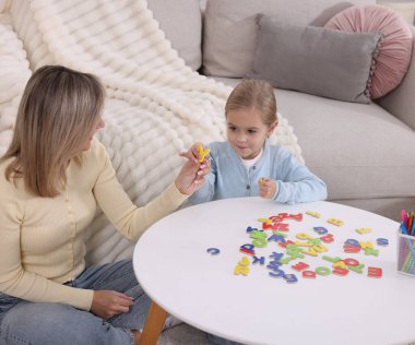 Anne, kızına beyaz masada alfabe öğretiyor.