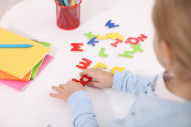 Beyaz masada harflerle alfabeyi öğrenen küçük kız, yakın plan.