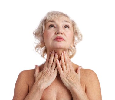 Yaşlı kadın beyaz arka planda boynuna dokunuyor.