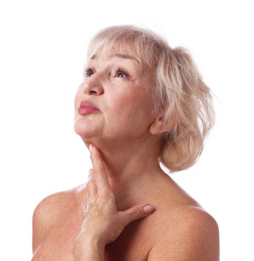 Yaşlı kadın beyaz arka planda boynuna dokunuyor.