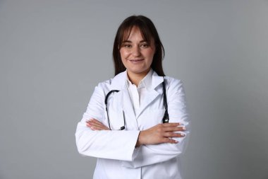 Gri arka planda steteskobu olan tıp üniformalı bir doktor.