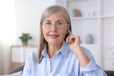 Evde işitme cihazı olan yaşlı bir kadın var.