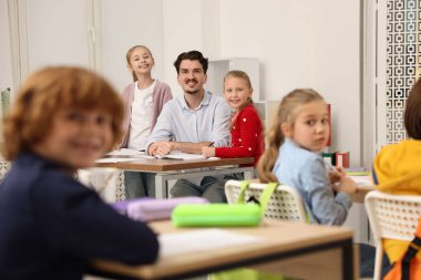 Sınıfta ders sırasında çocuklara bilgi açıklayan öğretmen, seçici odaklanma