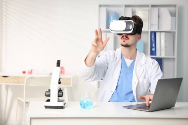 Modern teknoloji. Ofiste masasında sanal ekran kullanan kulaklıklı bir doktor. Metin için boşluk