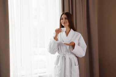 Bornozlu güzel bir kadın, pencerenin yanında sabah kahvesi var. Metin için boşluk