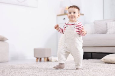 İlk adımlar. Evinde yerde yürüyen sevimli küçük bebek.