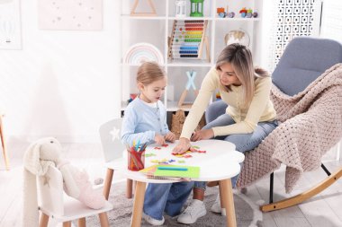 Anne, kızına beyaz masada alfabe öğretiyor.