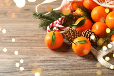 Taze mandalinalar, Noel şeker kamışları ve ahşap masada örgü şeklinde dallar, yakın plan. Bokeh ışıkları