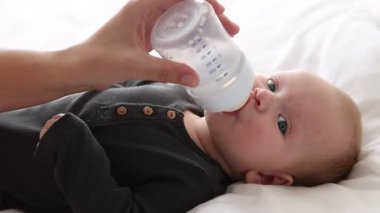 Anne bebeğini şişeyle besliyor.