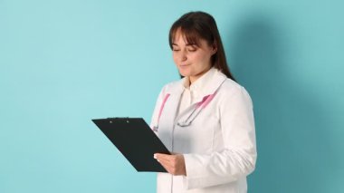 Açık mavi arkaplanda steteskop ve pano olan doktor.