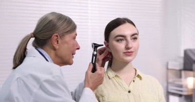 Duyma testi. Klinikte otoskopla hastaları muayene eden doktor..