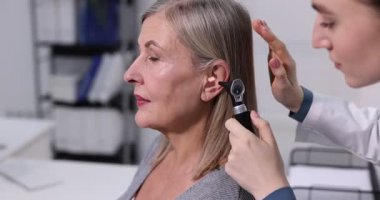 Duyma testi. Klinikte otoskopla hastaların kulaklarını muayene eden bir doktor. Kamera ileri gidiyor.