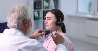 Duyma testi. Doktor klinikte hastanın işitsel kulaklığını ayarlıyor.