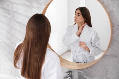 İçerideki aynanın yanında bornozlu güzel bir kadın.