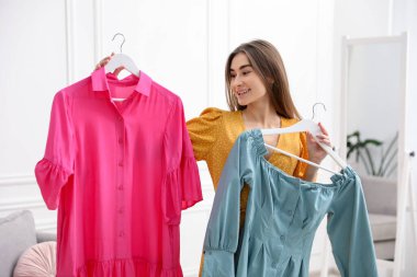 Kadın içeride pembe ve mavi elbiseler arasında seçim yapıyor.