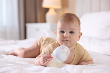Evde yatağında biberonla beslenen tatlı bir bebek. Metin için boşluk