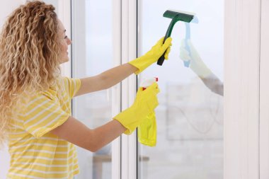 Evde cam sileceği ve deterjanı olan bir kadın var.