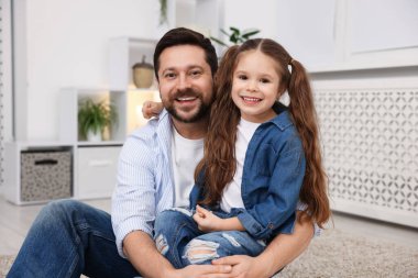 Mutlu baba evde yerde kızına sarılıyor. Aile bağı