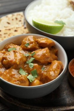 Lezzetli tavuk tikka masala, pirinç, kişniş ve kireç ahşap masada, yakın plan.