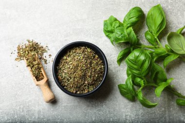 Açık gri masada taze ve kuru fesleğen yaprakları, düz yatıyordu.