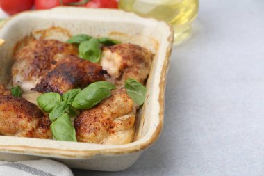 Lezzetli pişmiş tavuk butları ve fesleğen ve açık gri masada malzemeler, yakın plan. Metin için boşluk